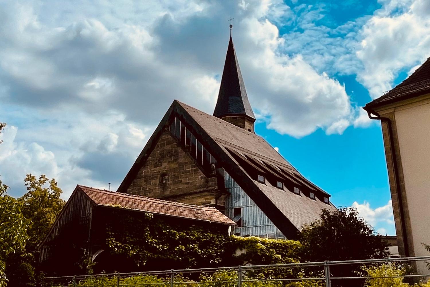 Blick vom Parkplatz auf die Kirche und das Pfarrbüro in Breitengüßbach
